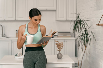 Sporty woman with book and tea at home stock photo