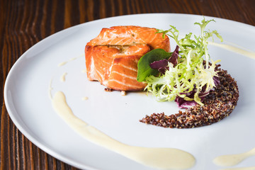 Salmon fish with kinua and sous on a white plate, close up