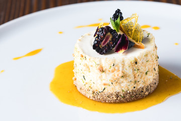 Vanilla ice cream, decorated with nuts flakes, blackberry, mint and flower on white plate