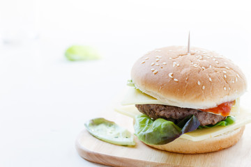 Burger mit Rindfleisch, Käse und frischem Salat auf einem Holzbrett serviert