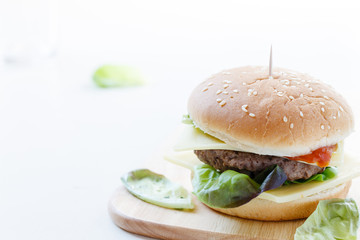 Burger mit Rindfleisch, Käse und frischem Salat auf einem Holzbrett serviert