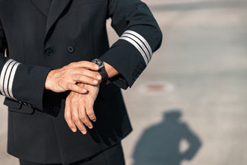 Caucasian pilot in uniform looking at watch in airport