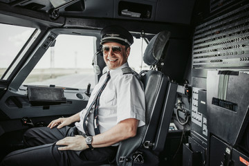 Smiling pilot in cockpit posing for camera - obrazy, fototapety, plakaty