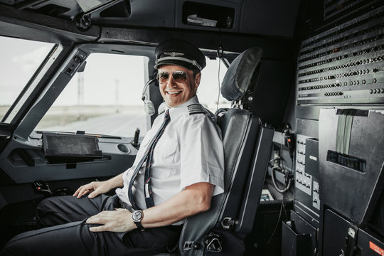Smiling pilot in cockpit posing for camera