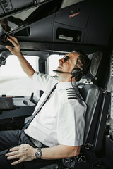 Caucasian happy adult man in uniform piloting perfectly modern airliner