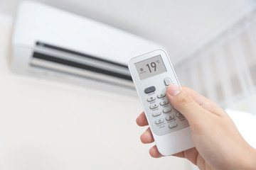 Hand with remote directed on air conditioner.