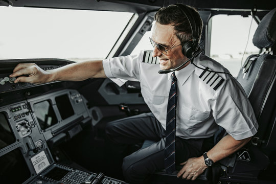 Caucasian happy adult man in uniform piloting perfectly modern airplane