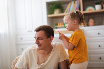 child with Down syndrome plays with dad, room