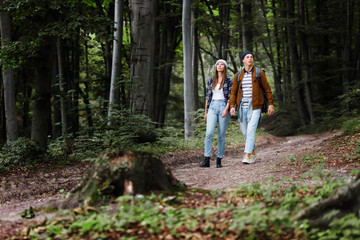 Naklejka na ściany i meble Caucasian couple of friends walking with backpacks in forest