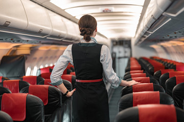 Caucasian stewardess is on duty on board of airliner