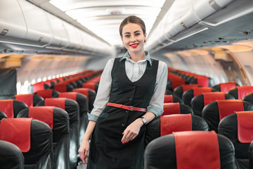 Caucasian attractive stewardess is on duty on board of airplane