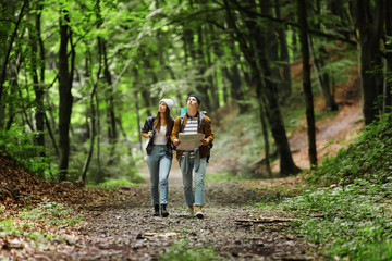 Young tourists couple holding map walking and studying nature in the forest