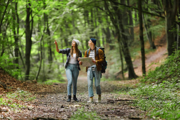 Couple teens travel with backpack in the forest and looking map the route go to destinations
