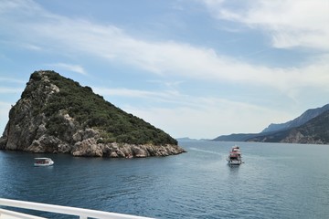 Fototapeta na wymiar Turtle Island with a passing boat on the Mediterranean Sea