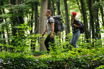 Happy young couple standing together with backpacks while hiking in the forest