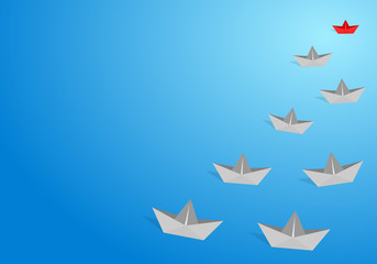 Red origami paper boat leading gray staff ones go on the route on blue background. Leadership and teamwork concept.