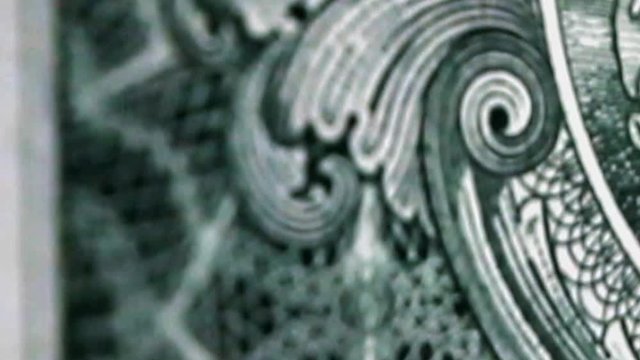 Close-up view of turning receding dollar bill. One dollar is rotates on black background, macro view.