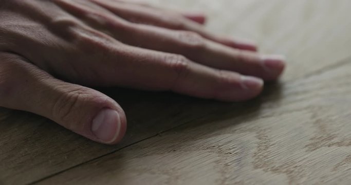 Slow motion man hand check quality of glued oak wood surface