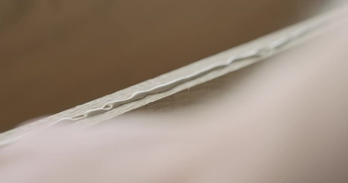 Slow motion closeup man spreading wood glue on aok board with finger