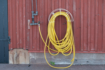 Yellow water-hose on red wall - Landscape