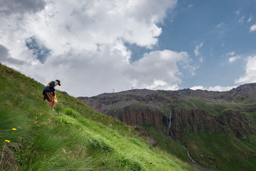 Fototapeta premium girl descends alone from a green hill in the mountains