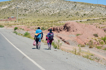 Fototapeta premium Road view with two people walking and mountains in the surroundings of Macha, Potosi, Bolivia