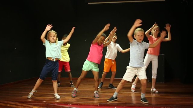Positive children studying modern style dance in class indoors