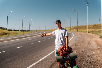 Travel man hitchhiking. Backpacker on road