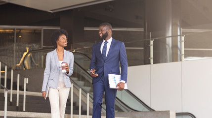 Two african american employees leaving office building for coffee break