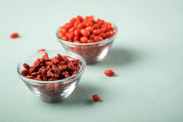 Frische und getrocknete Goji-Beeren Superfood in Glas Schale auf Mint Grün Pastell Hintergrund