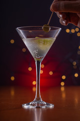 male hand picking an olive with a stick over a cocktail