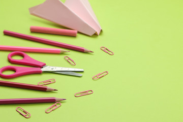 back to school. stationery, school supplies colored pencils and a paper plane and scissors on a bright green background.
