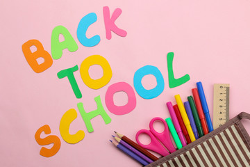 back to school. stationery, school supplies, text and pencil case with pencils on a bright pink background. top view.