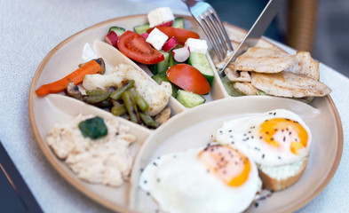 Close up view of plate with eggs and vegetables standing on the table