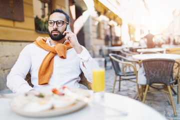 Fototapeta na wymiar Beard man talking mobile phone while eating at the cafe