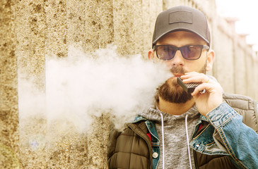 man with a beard smokes an electronic cigarette