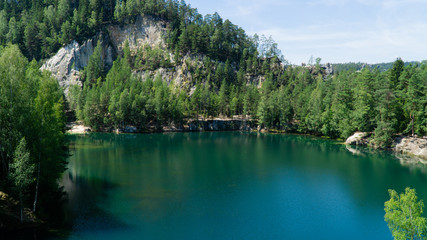 Flooded sandpit in Adrspach Rocks, lake with beautiful clear turquoise water hidden in the middle of forest, Czech Republic