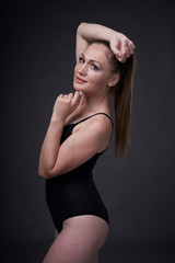 flexible sexy girl poses on a black grey background in the fitting clothes baud