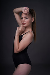 Fototapeta premium flexible sexy girl poses on a black grey background in the fitting clothes baud