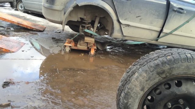 Evacuation of an old, broken car that has no wheel. Loading the car on a truck for transportation for repair.