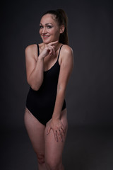 flexible sexy girl poses on a black grey background in the fitting clothes baud