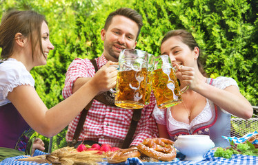 Young people in Tracht, Dindl and Lederhosen having fun in Beer garden