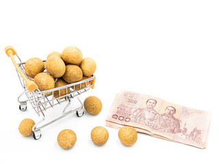 Fruit trading concept. Longan in cart and Thai banknote isolated on white background