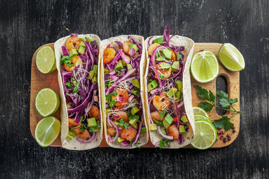 Tacos with shrimps., avocado and red onion on a wooden table. Traditional American fast food. Top view shot, directly above.