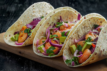 Tacos made of prawns, avocado, red onion, cabbage and lime on a table. Delicious Mexican cuisine...
