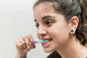 Young woman brushes her white teeth with a toothbrush.