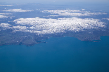 Clouds and mountains covered in snow viewed from inside the aircraft. Travel concept with copy space.