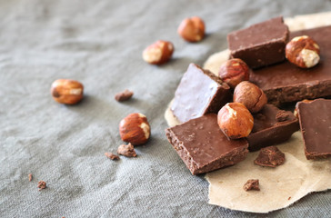 Dark chocolate and hazelnuts on a grey background.