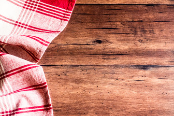 Striped red and white napkin on an old wooden brown background, top view. Image with copy space. Kitchen table with a towel - top view with copy space. 
