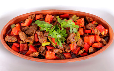 Turkish meats peppers tomatoes and greens in a clay pot and a white plate